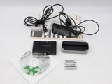 Compact digital camera kit with cables, battery, charger cradle, and software discs.