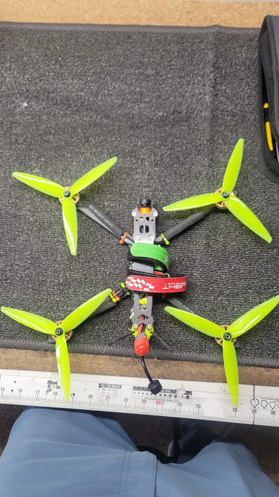 FPV drone with four green propellers and compact frame, ready to fly