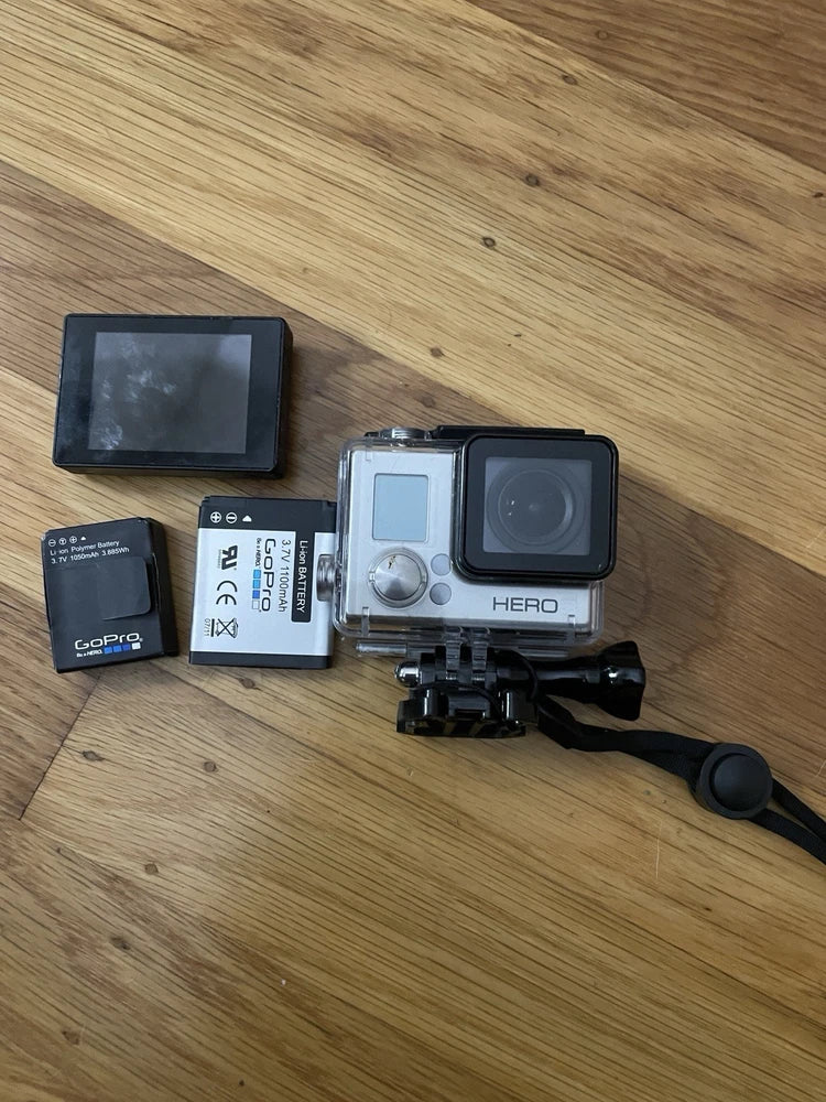 GoPro HERO action camera with waterproof housing, lens, LCD, mounts, and battery
