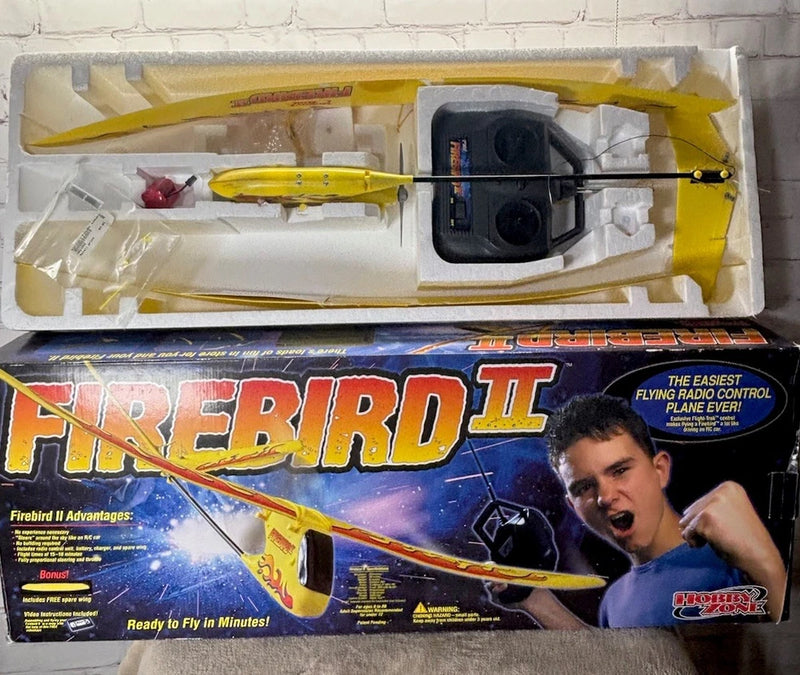 Yellow RC airplane model with red flame decals, in retail packaging tray