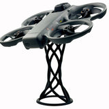 Gray drone on black desktop display stand with curved cable supports