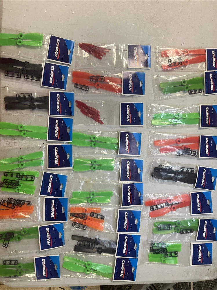 Drone replacement propeller blade lot with multiple packaged green, orange, red, and black blades