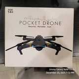 Black pocket drone with four propellers and centered camera, shown on product box