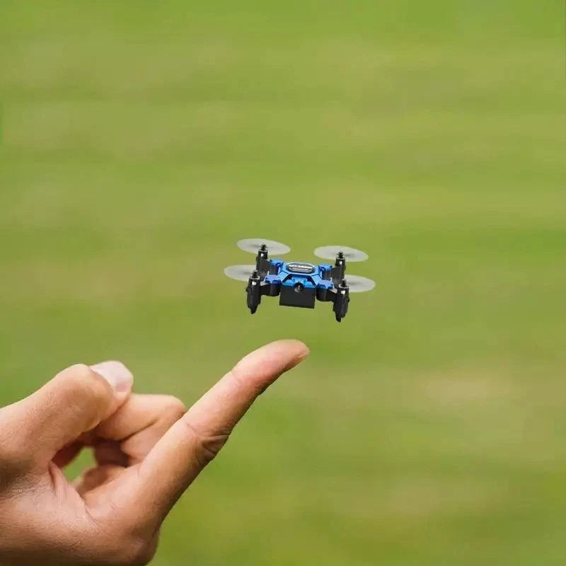 Mini folding quadcopter drone with camera hovering above an open hand