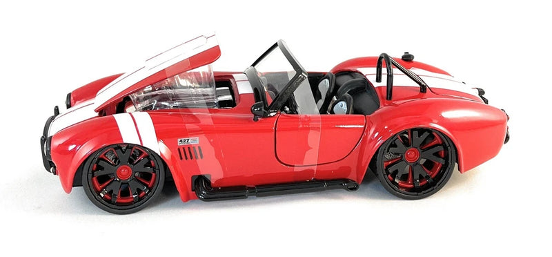 Red 1:24 scale Shelby Cobra model car with black wheels, hood open