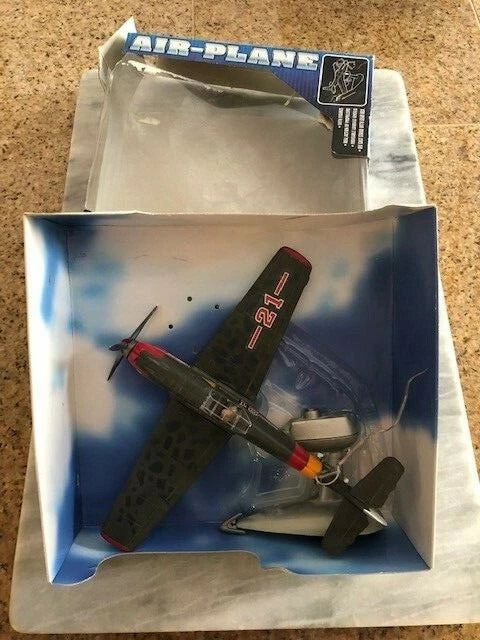 Toy fighter airplane model in open box, blue sky graphics, red marking on fuselage
