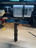 Black handheld gimbal stabilizer with mounted Sony action cam