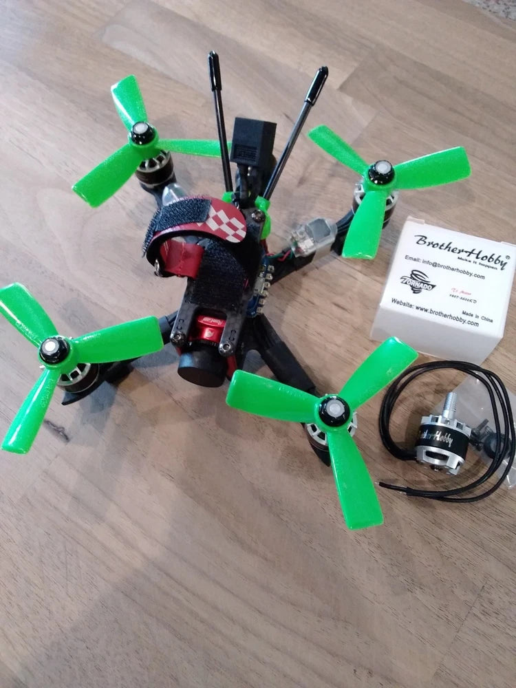 FPV racing quadcopter with green propellers, carbon-fiber frame, antenna and motor wires