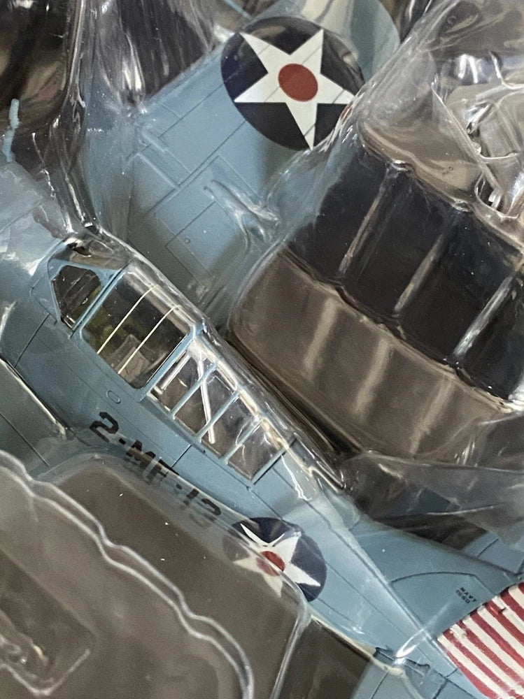 Blue military aircraft scale model in clear blister packaging with US flag decal