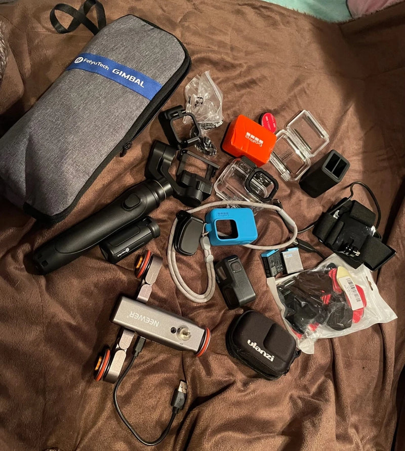 Action camera and gimbal accessory bundle with gray carry case, mounts, batteries, and cables