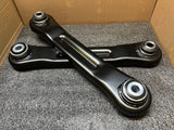 Rear toe control arms: dark metal bars with rubber bushings and mounting ends