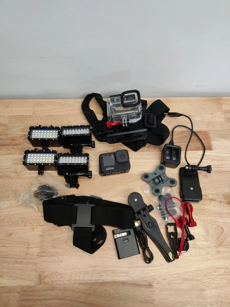 Black action camera bundle with battery, charger, mounts, straps, and LED lights