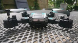 Black quadcopter drone with central camera module and four propellers
