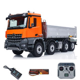 Orange 8x8 RC dump truck with tipping bed, plus remote controller and power accessories
