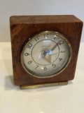 Vintage analog clock with wooden case, brass bezel, and cream dial with black numerals