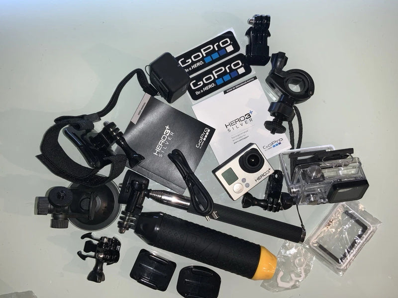 Silver action camera bundle with GoPro Hero 3+ camera, mounts, and waterproof housing