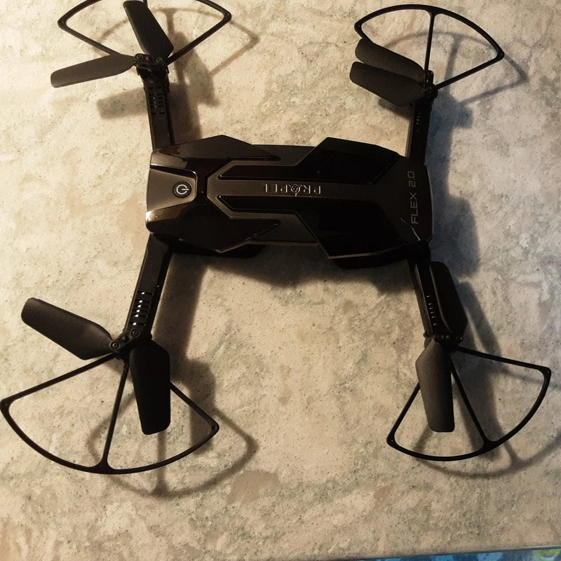 Black folding RC drone with four propellers, cracked casing for parts repair