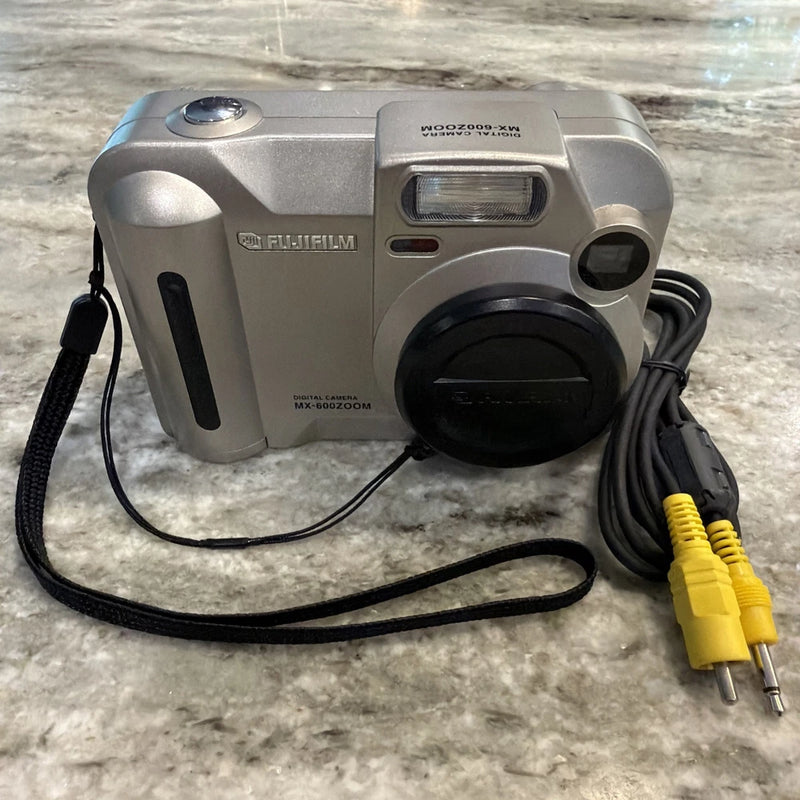 Fujifilm MX-600Zoom compact camera with lens cap and yellow/white audio-video cables