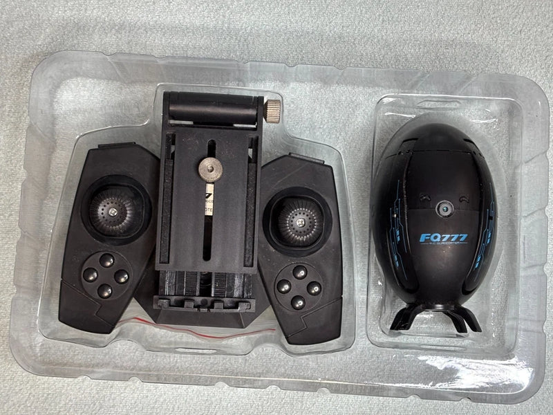 Black flying egg drone and remote controller in molded tray