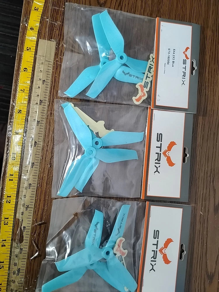 Blue drone propeller blade set in clear packaging, four blades visible.