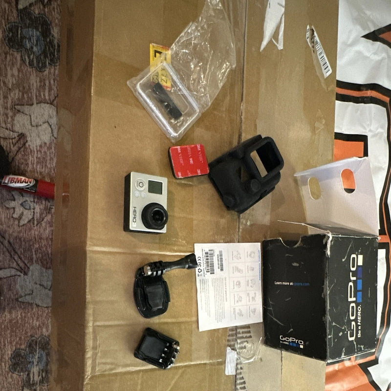 GoPro HERO3 action camera with waterproof case and assorted mounts, cables, and papers