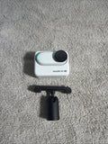 Arctic white tiny action camera with front lens and black mounting grip