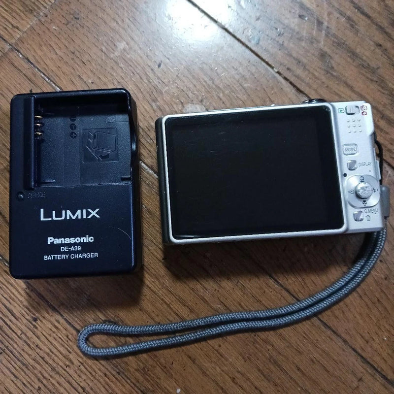 Compact digital camera with screen and Panasonic battery charger, front and back shown