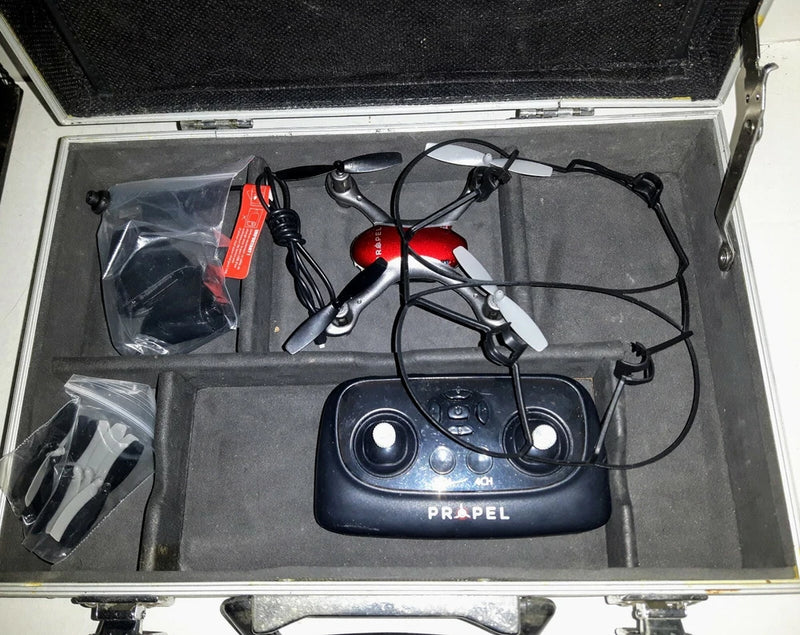 Small quadcopter drone with controller and cables, stored in open hard case