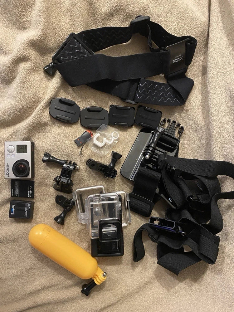 GoPro action camera bundle with silver camera, waterproof case, straps, mounts, yellow float.