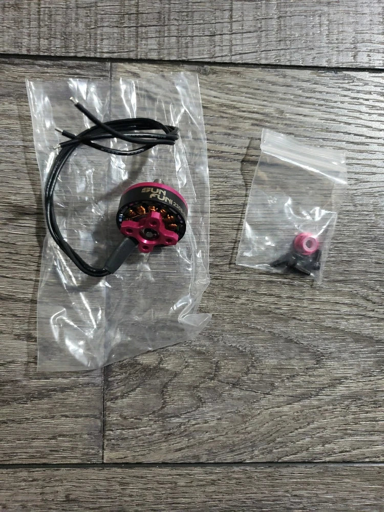 Red brushless FPV motor with black wires and small mounting parts in plastic bag