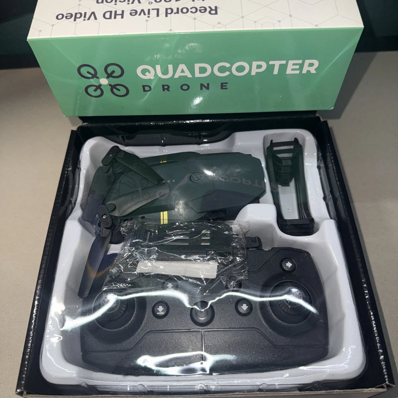 Black quadcopter drone with camera, folded arms and remote controller in open box