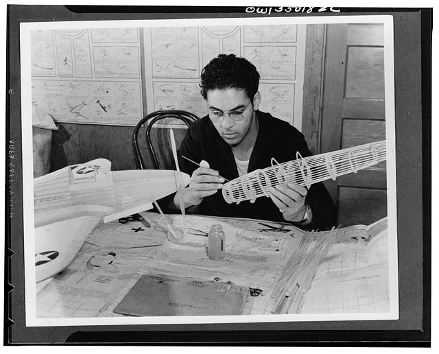 Black-and-white vintage model airplane hobby photo of man assembling a model