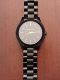 Michael Kors Slim Runway watch with black dial, gold markers, and stainless steel bracelet
