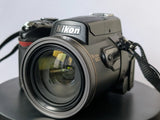 Nikon Coolpix digital camera body with large lens, front view and strap.