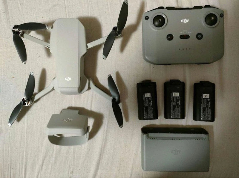 White quadcopter drone, RC controller, three batteries, and charging case set