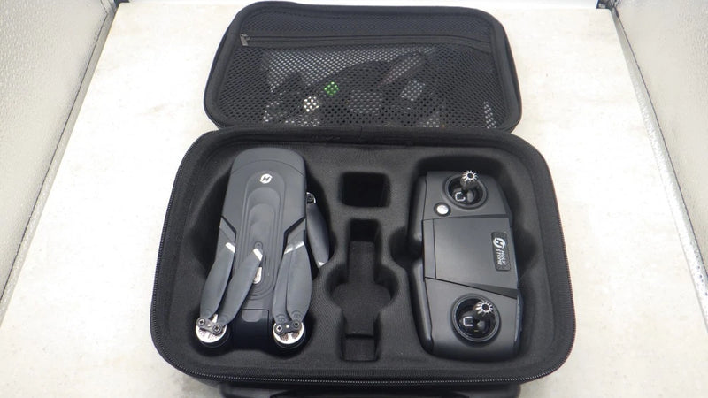 Black carrying case with controller and drone accessories, including landing gear and prop parts