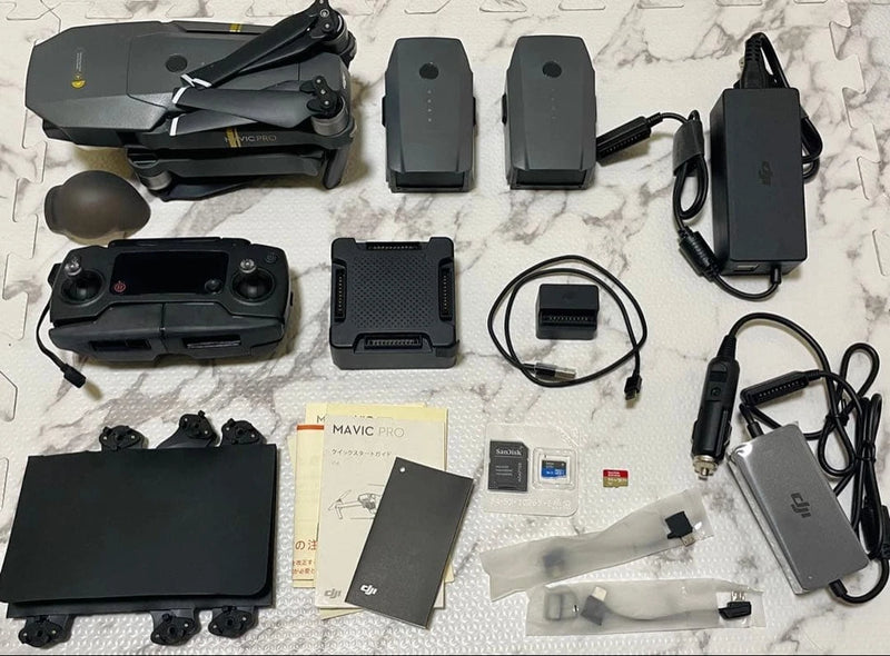 Foldable quadcopter drone with remote controllers and charging adapters, accessories laid out