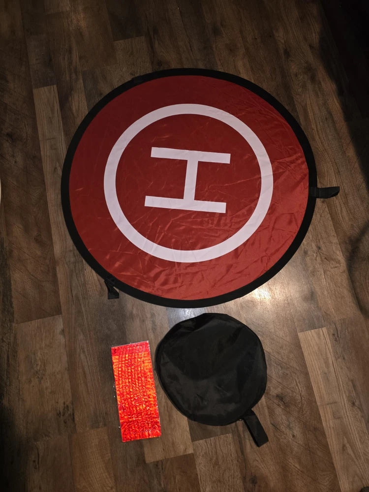 Round red drone landing pad with white center mark, black edge, reflective strip and pouch