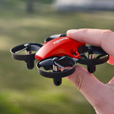 Red mini quadcopter drone with four rotors, held in hand, close-up view
