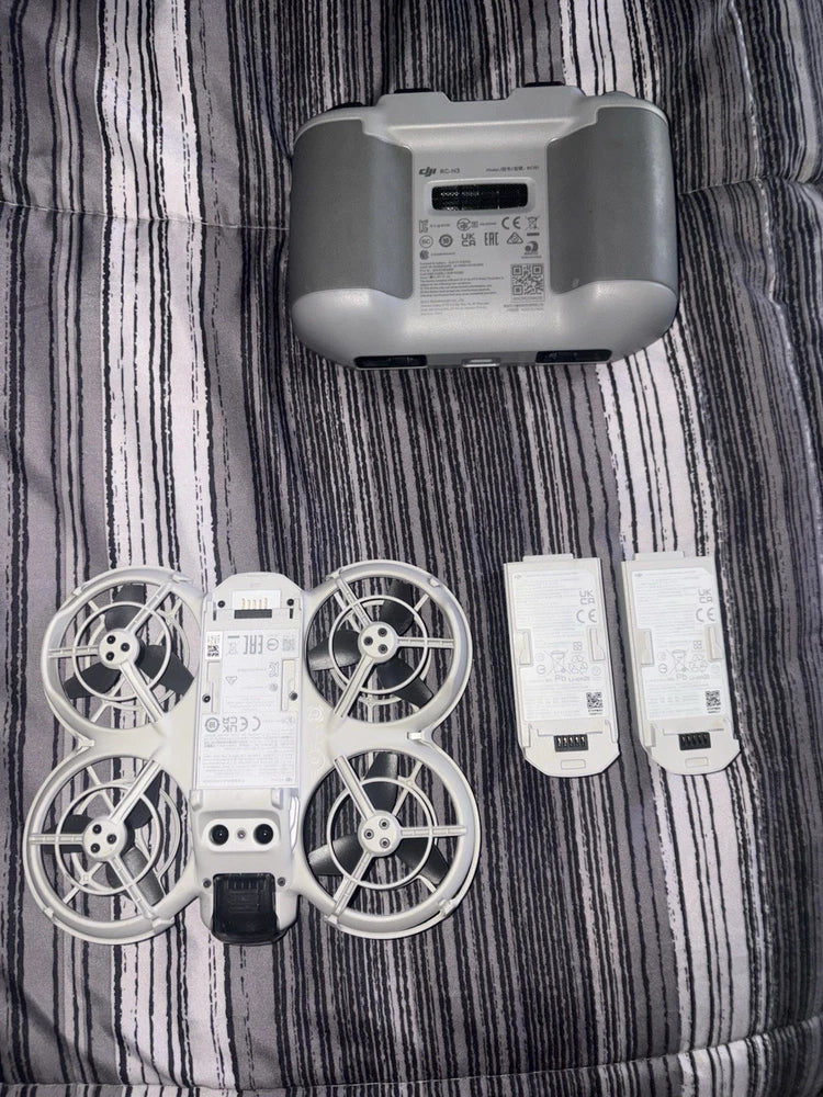 Foldable quadcopter drone with white-gray body, propellers, two batteries, and remote controller