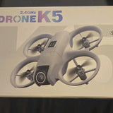 K5 quadcopter drone with front camera and four propellers, light gray body