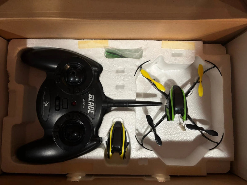Drone and black remote controller with folded propellers, packed in a box