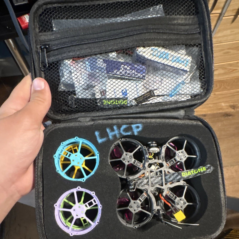 FPV drone frame and motors in black zip carrying case, prop rings visible