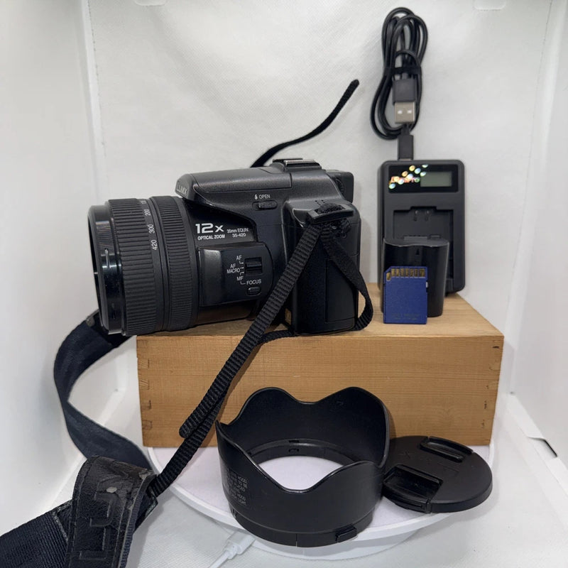 Black Panasonic Lumix digital camera with lens, charger, battery, strap, and case