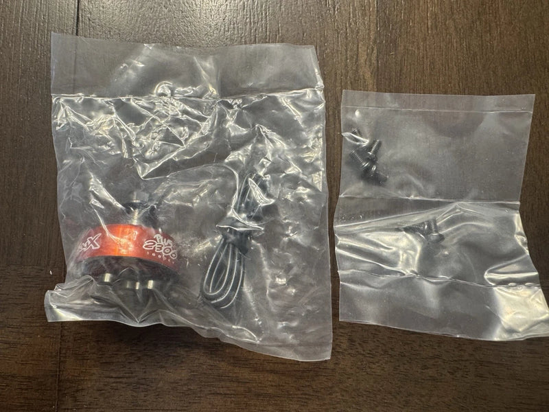 Orange RC drone motor in small plastic packaging bag with included wiring connectors