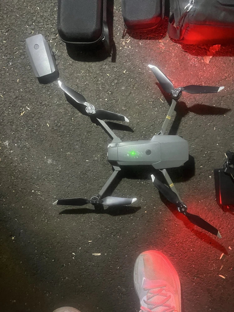 Camera drone with visible propellers and front LED lights, powered on