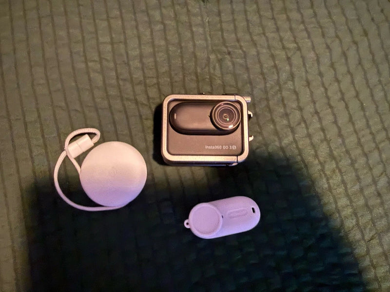 Black compact action camera with front lens and protective frame