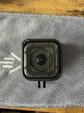 Black waterproof action camera front with wide-angle lens and mounting tabs