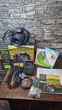 Black Fujifilm bridge digital camera with 30x zoom, charger, cables, manuals and discs