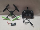 Stunt quadcopter drone with green arms, black propellers, and RC controller with cable.